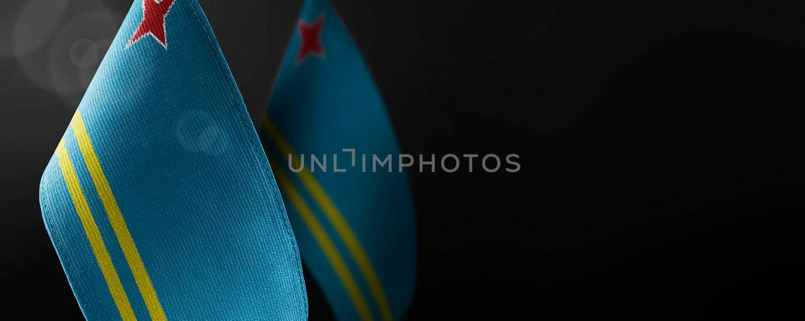 Small national flags of the Aruba on a dark background.