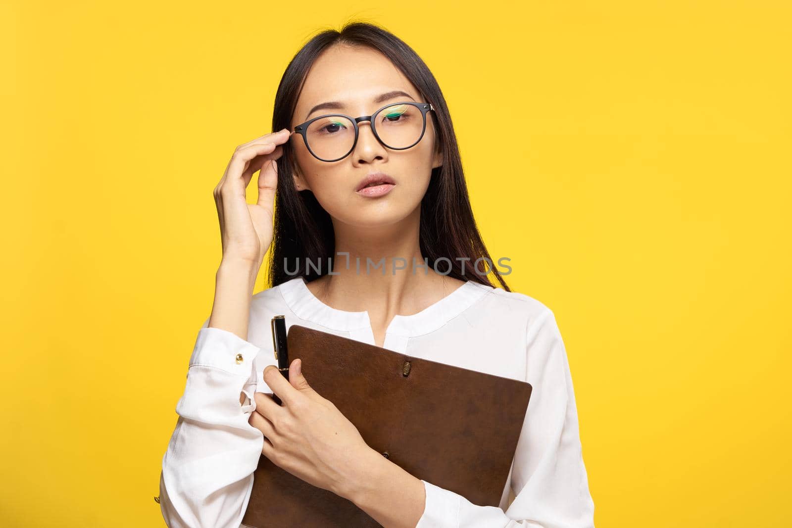 Business woman in glasses with notepad in hands executive secretary yellow background. High quality photo