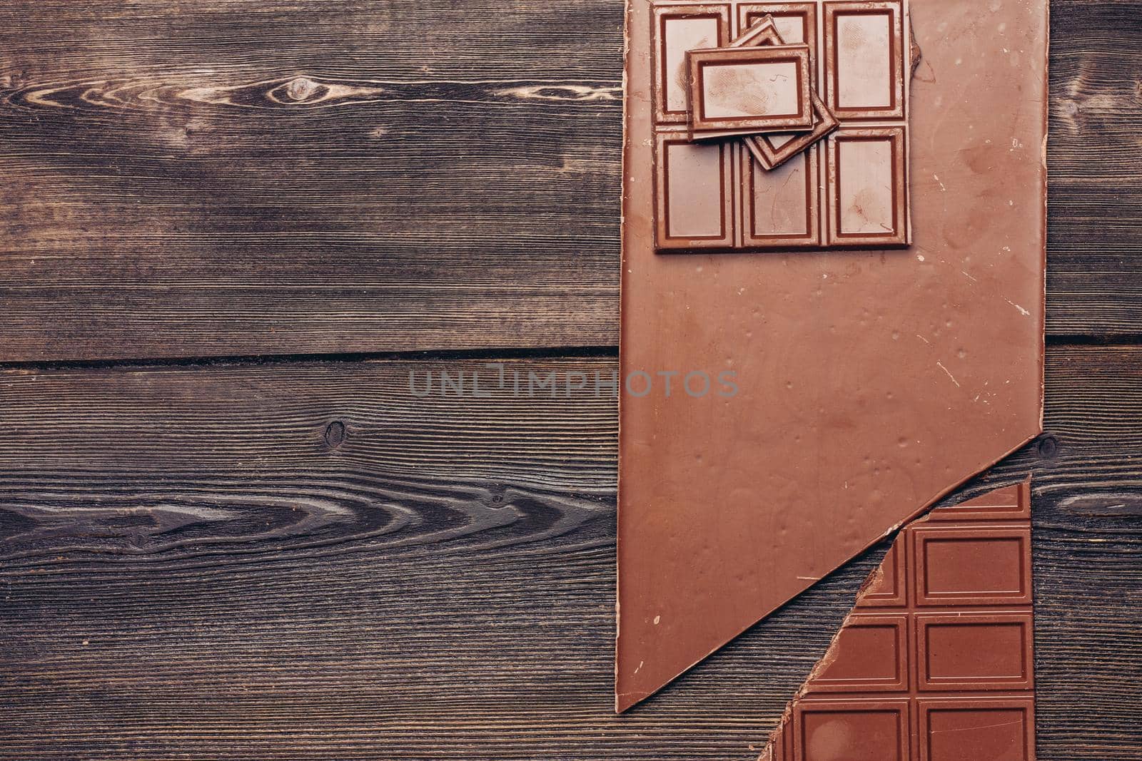 bar of chocolate on a wooden background cubes diagonal sweets candy. High quality photo