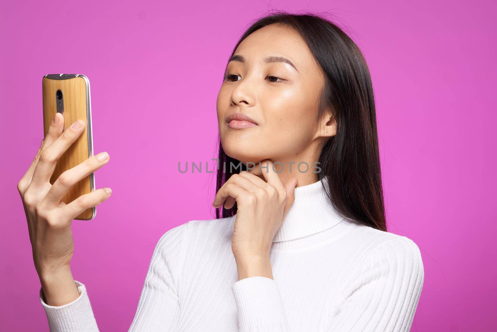 pretty asian woman white sweater phone in hand communication message. High quality photo
