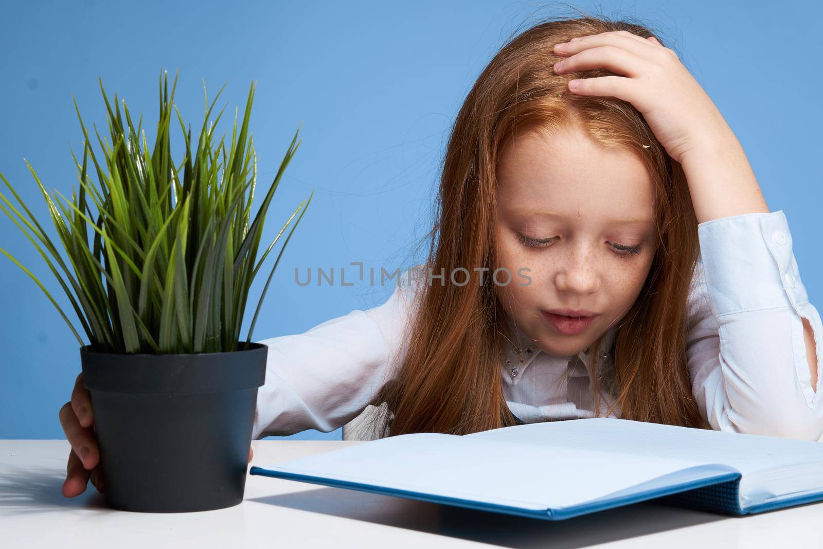 emotional red-haired girl sitting at the table home lessons learning. High quality photo
