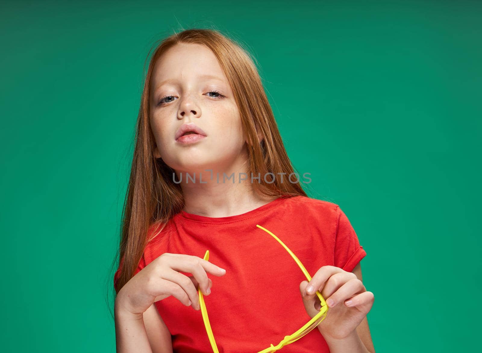 cute girl red hair gestures with hands emotions childhood school Green background. High quality photo