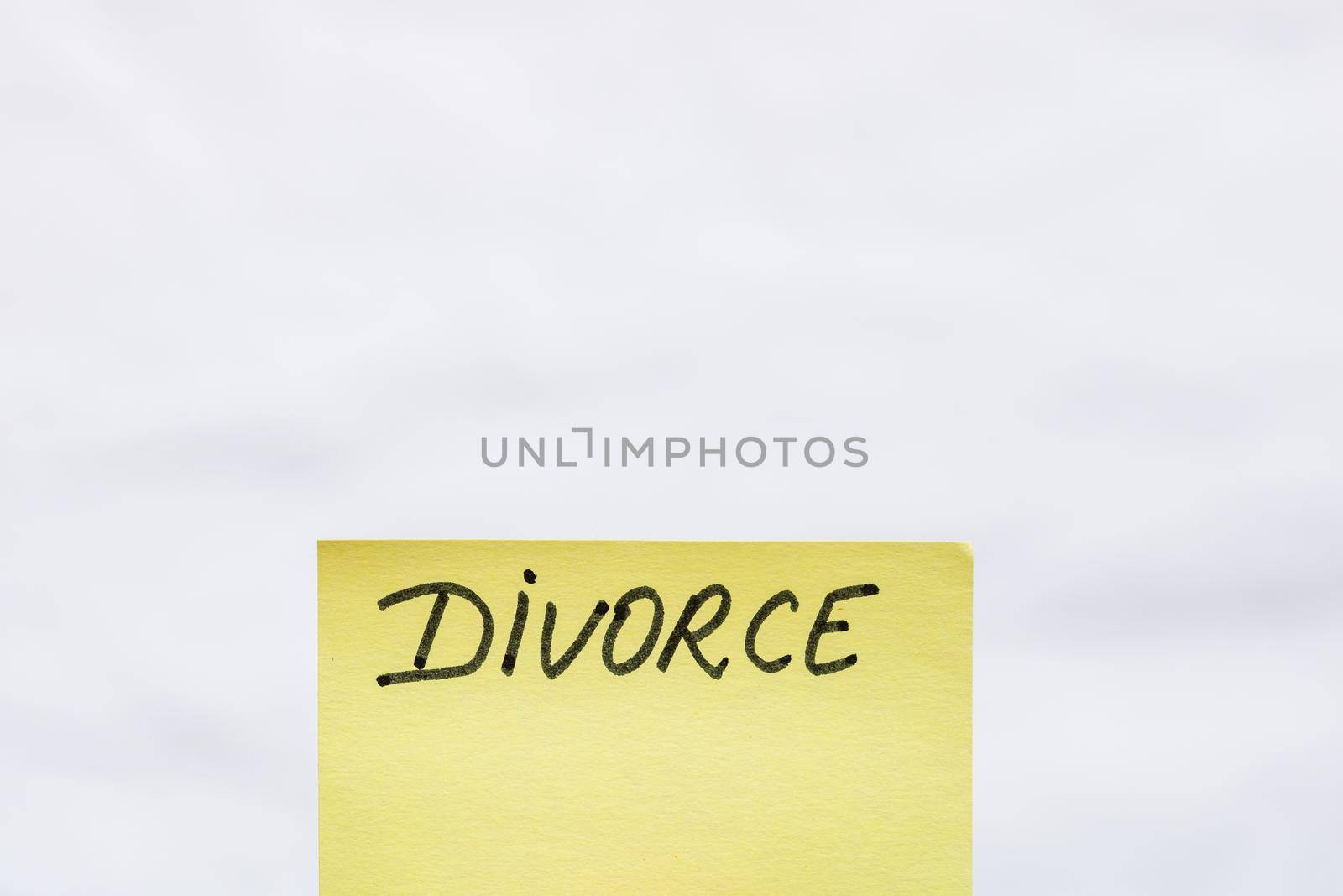 Divorce handwriting text close up isolated on yellow paper with copy space.