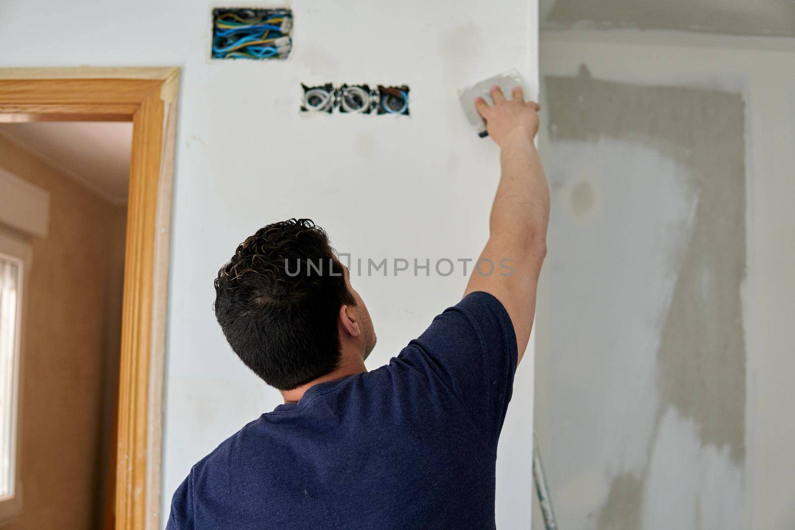 Painter working with spatulas in a room white