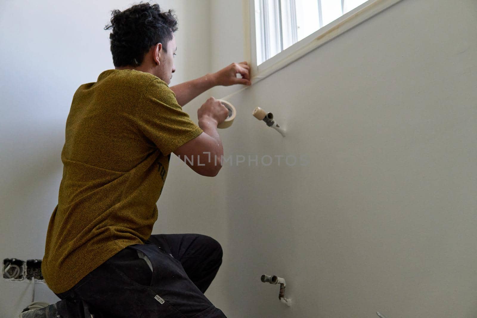 Painter preparing to paint a room with masking tape