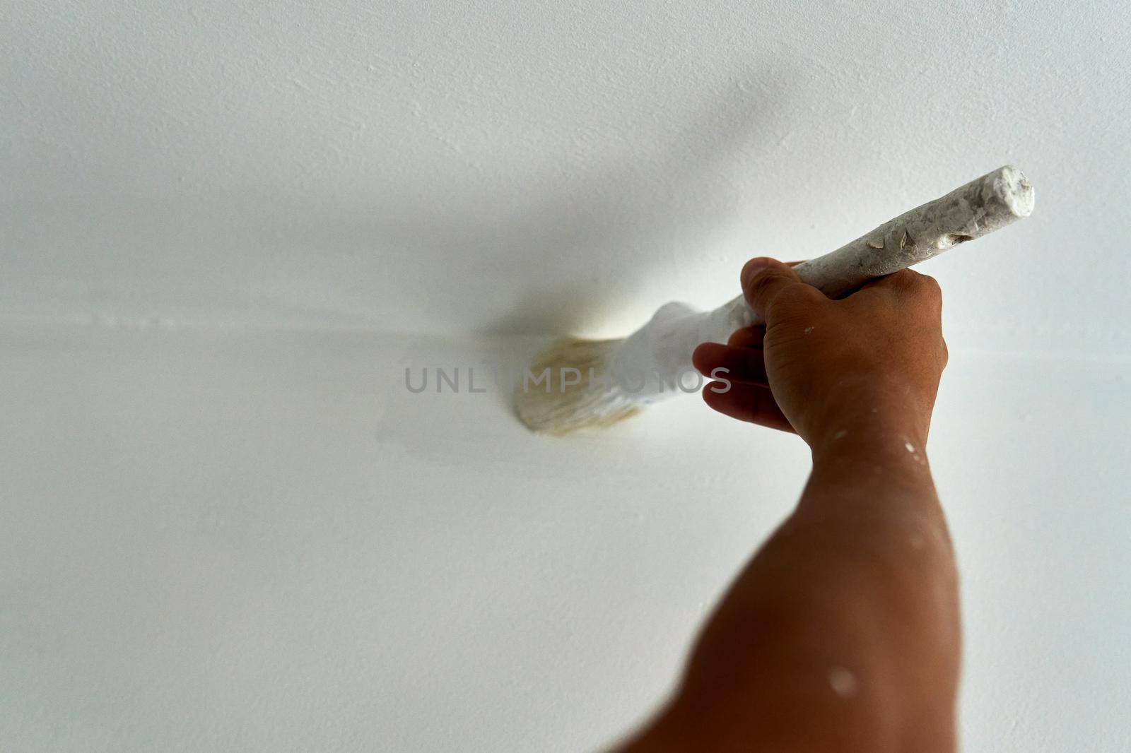 Painter painting a white room with a brush