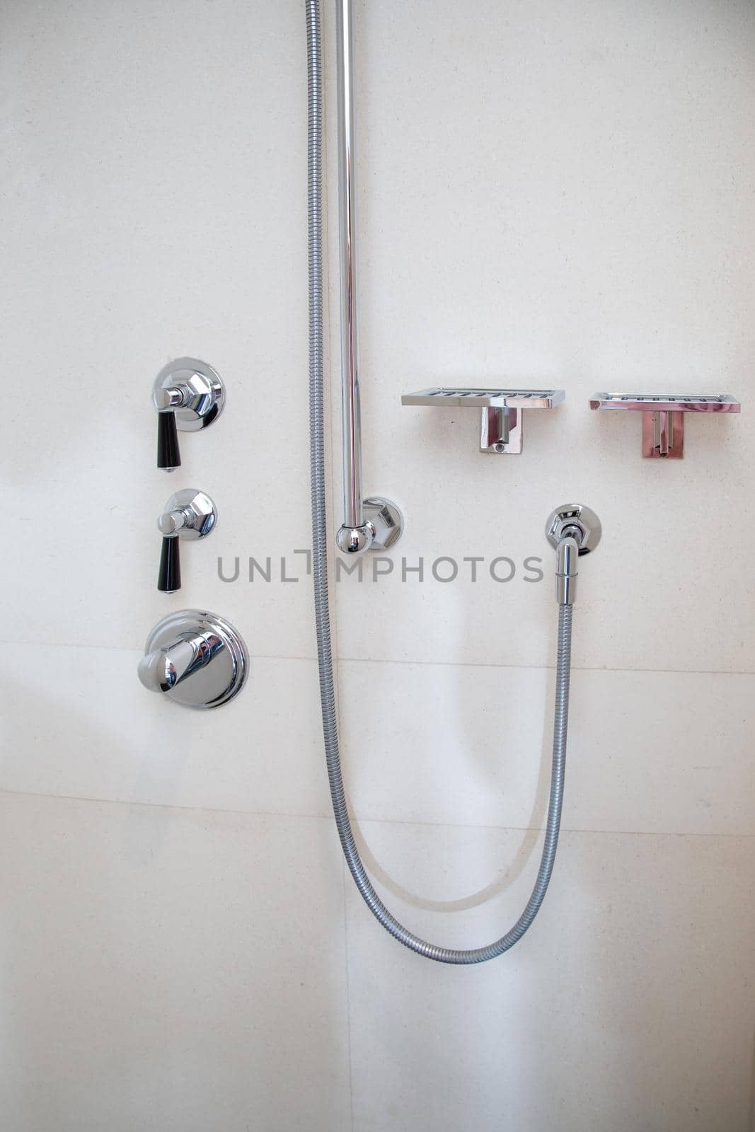 Chrome metal shower faucets in the bathroom by galinasharapova