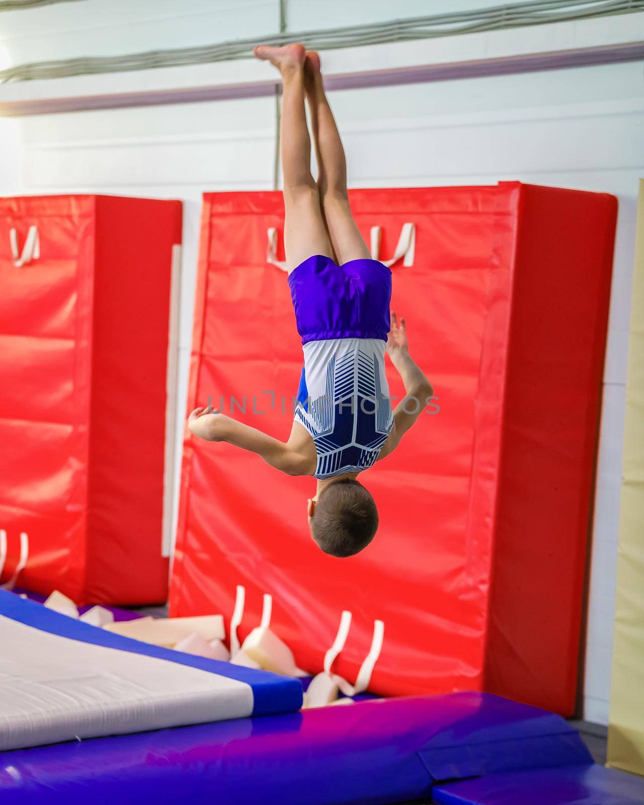 A young guy performs a jump somersault, in training. Gymnastics.