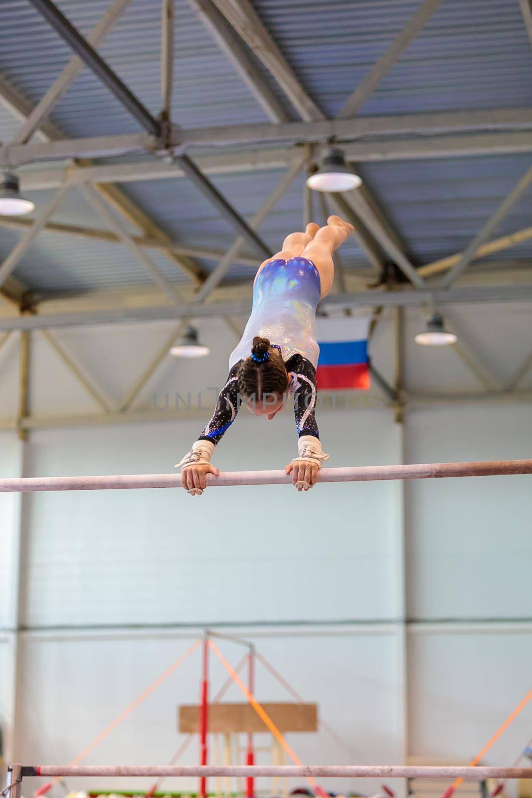 A girl in sportswear performs an exercise on the uneven bars. Rhythmic gymnastics, training in the hall. Moscow, Russia May 19, 2019