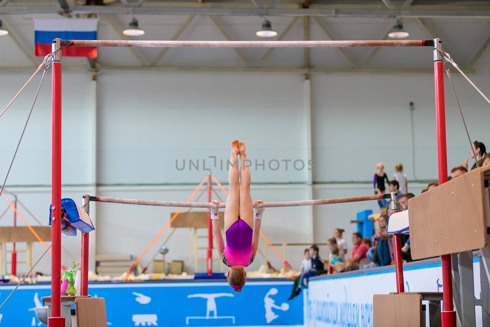 A girl in sportswear performs an exercise on the uneven bars. Rhythmic gymnastics, training in the hall. Moscow, Russia May 19, 2019