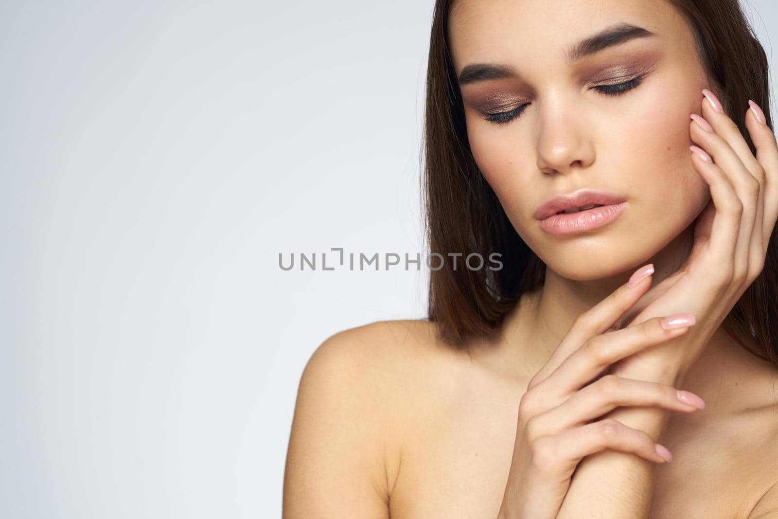 Woman with long hair bared shoulders clean skin body care light background. High quality photo