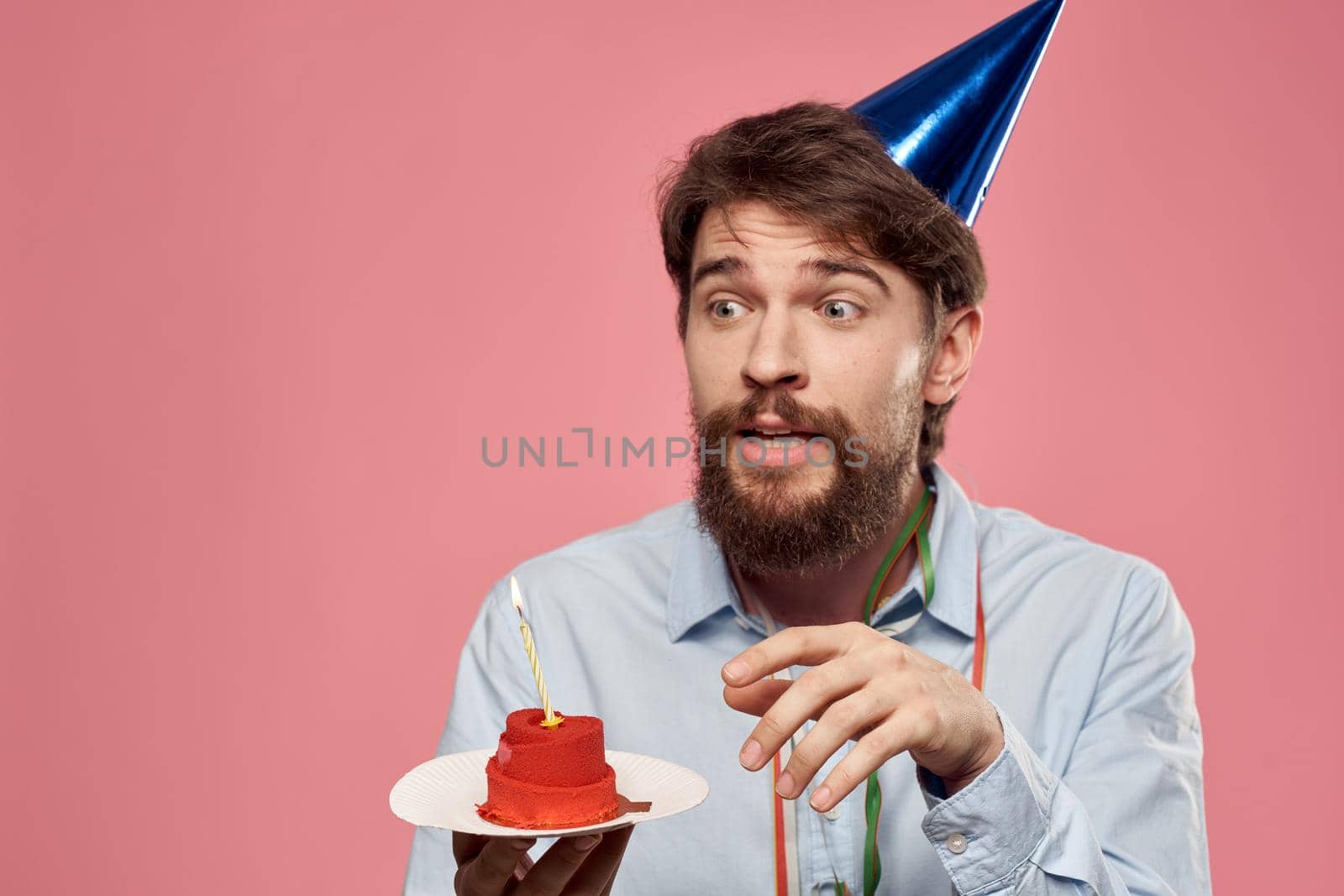 Birthday of a man with a cake and with a candle on a pink background. High quality photo