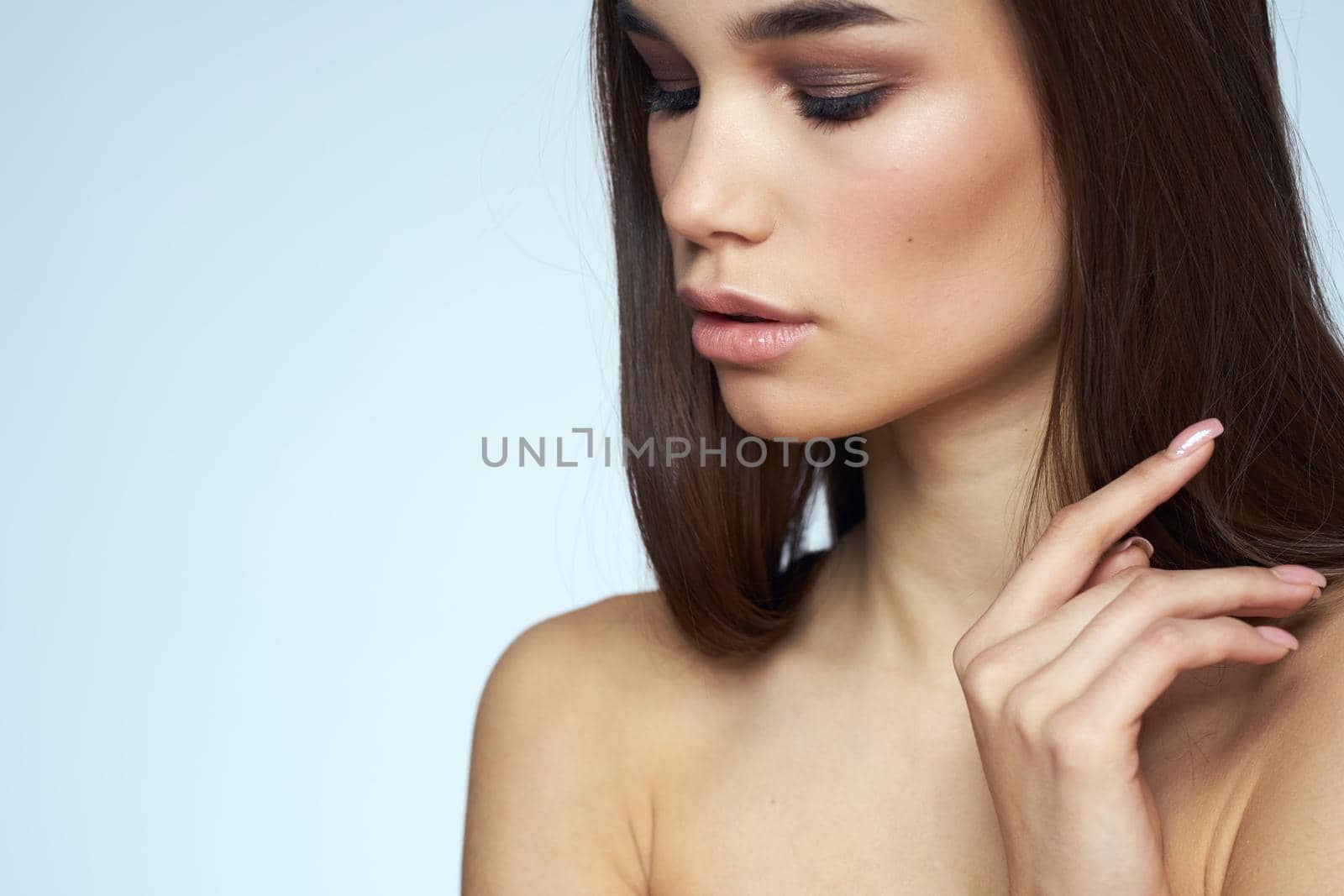 Woman with naked shoulders long hair clean skin cropped view blue background. High quality photo