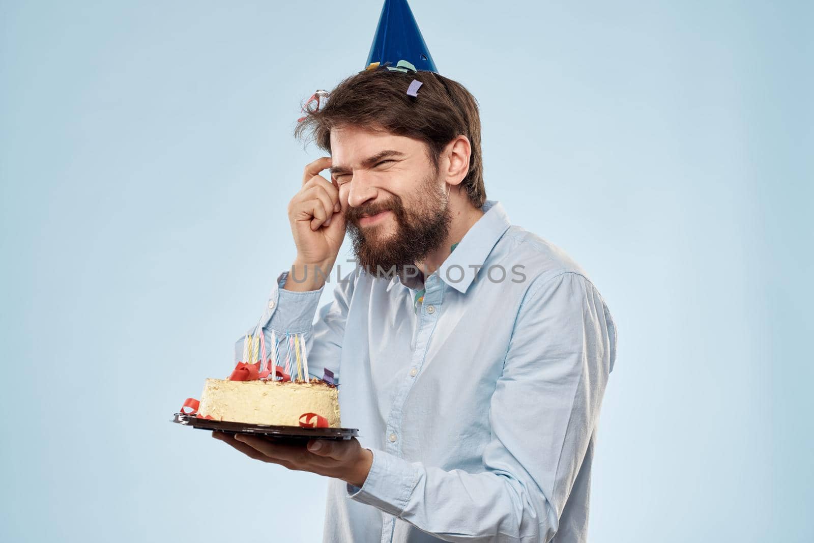 A man in a shirt with a cake in his hands and a festive cap on his head. High quality photo