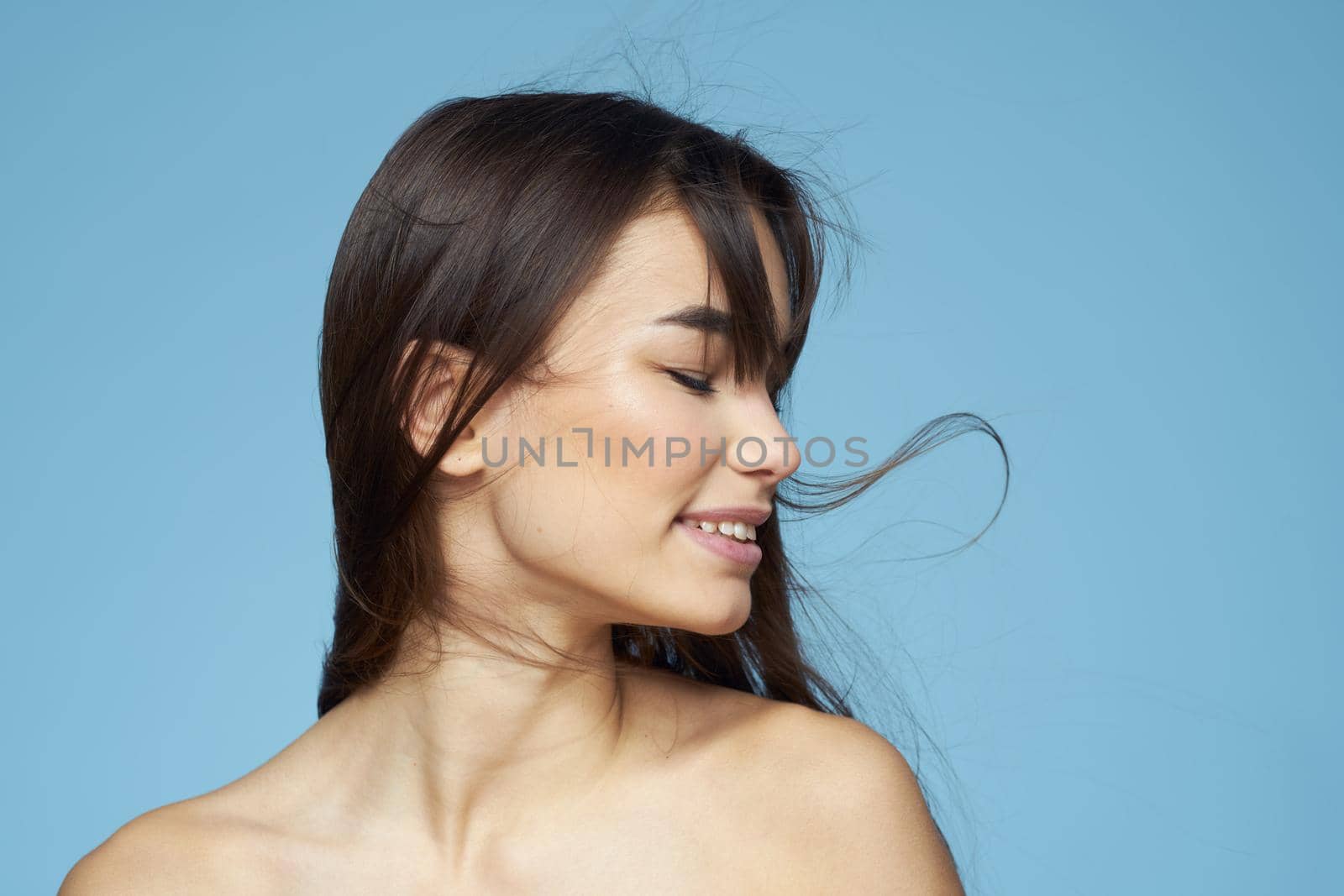 Woman with naked shoulders long hair cosmetics attractive look blue background. High quality photo