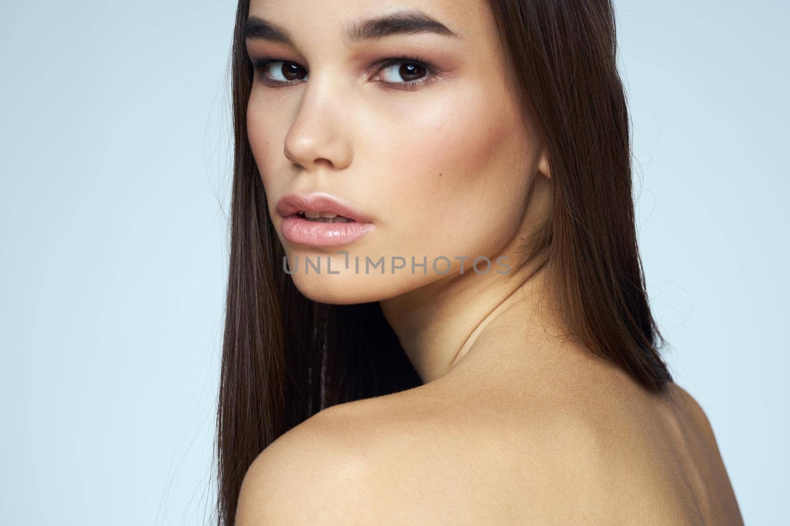 Pretty brunette with bared shoulders long hair body care blue background. High quality photo