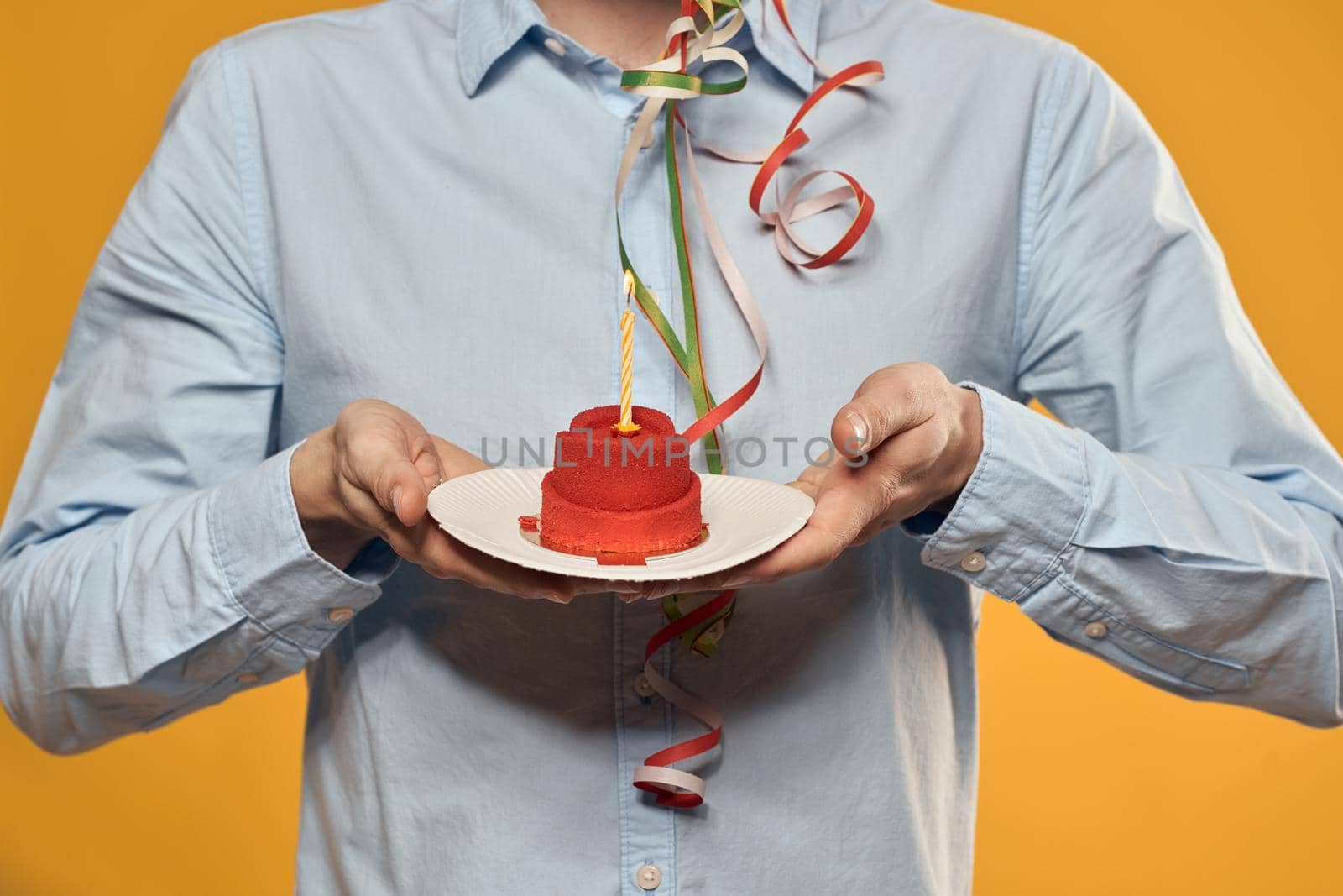 Cheerful man with a cake on a yellow background birthday holidays cap on his head. High quality photo