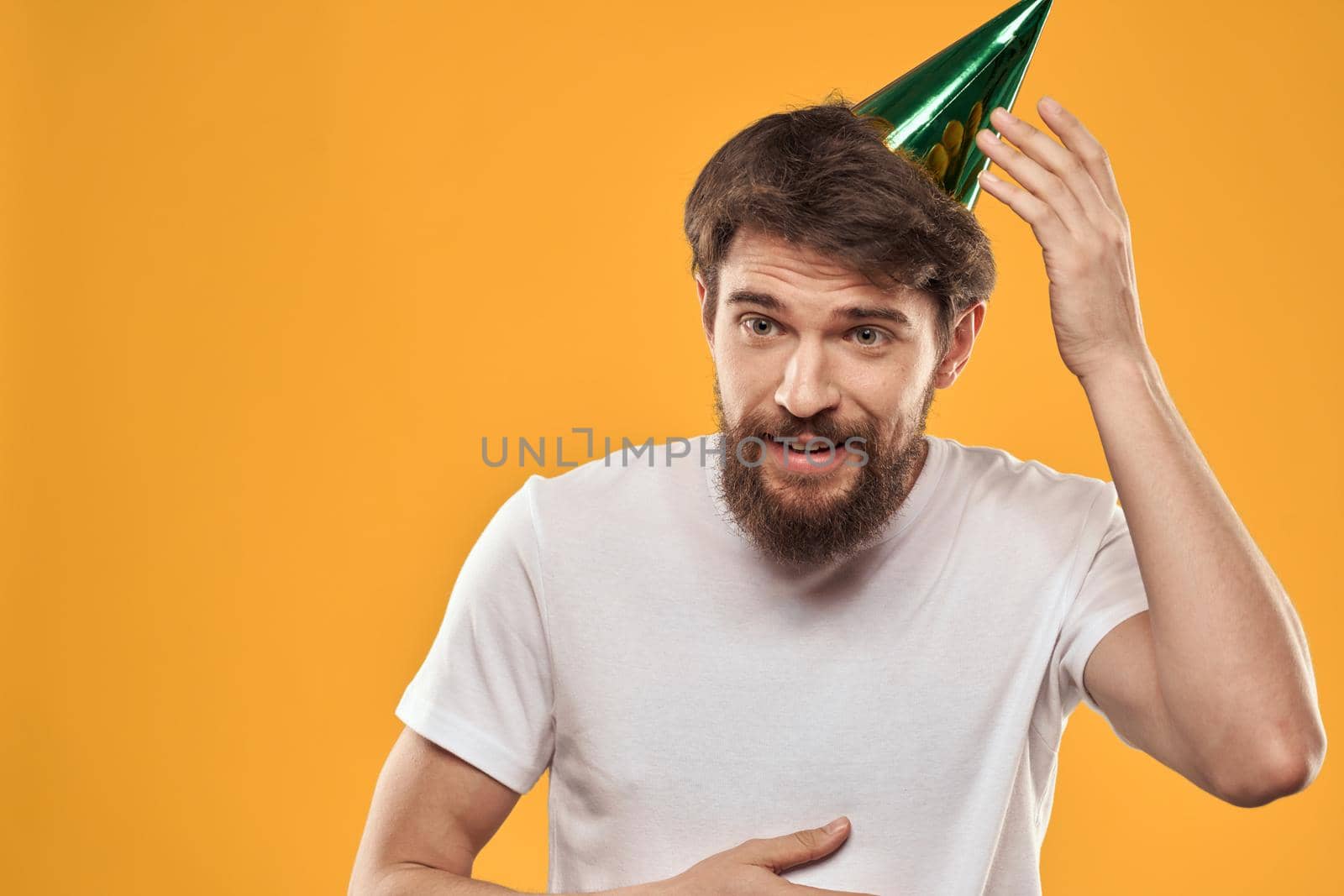 Man with cake on yellow background birthday party hat cropped view. High quality photo