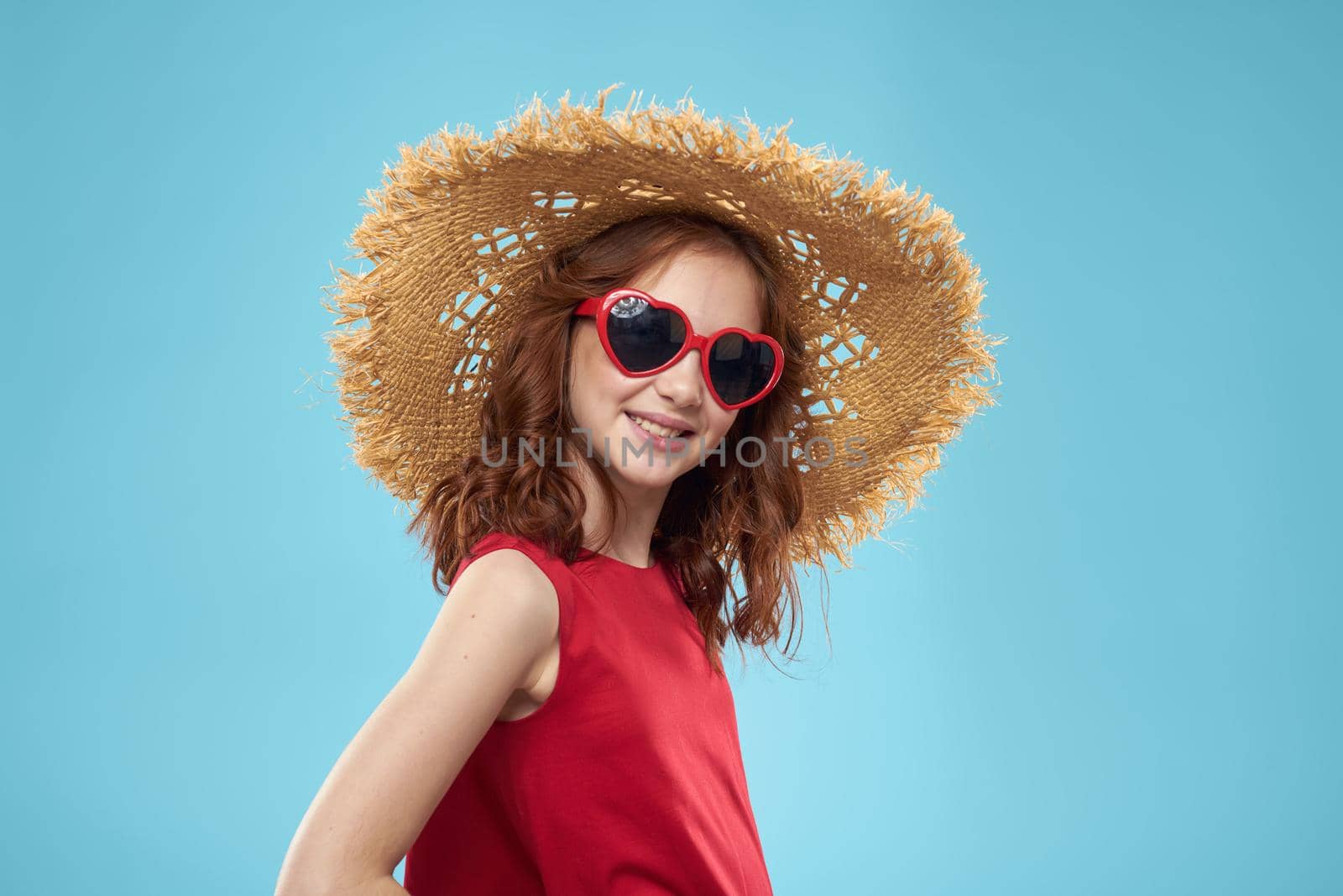 Girl in a beach Straw hat in sunglasses curly hair fun blue background. High quality photo