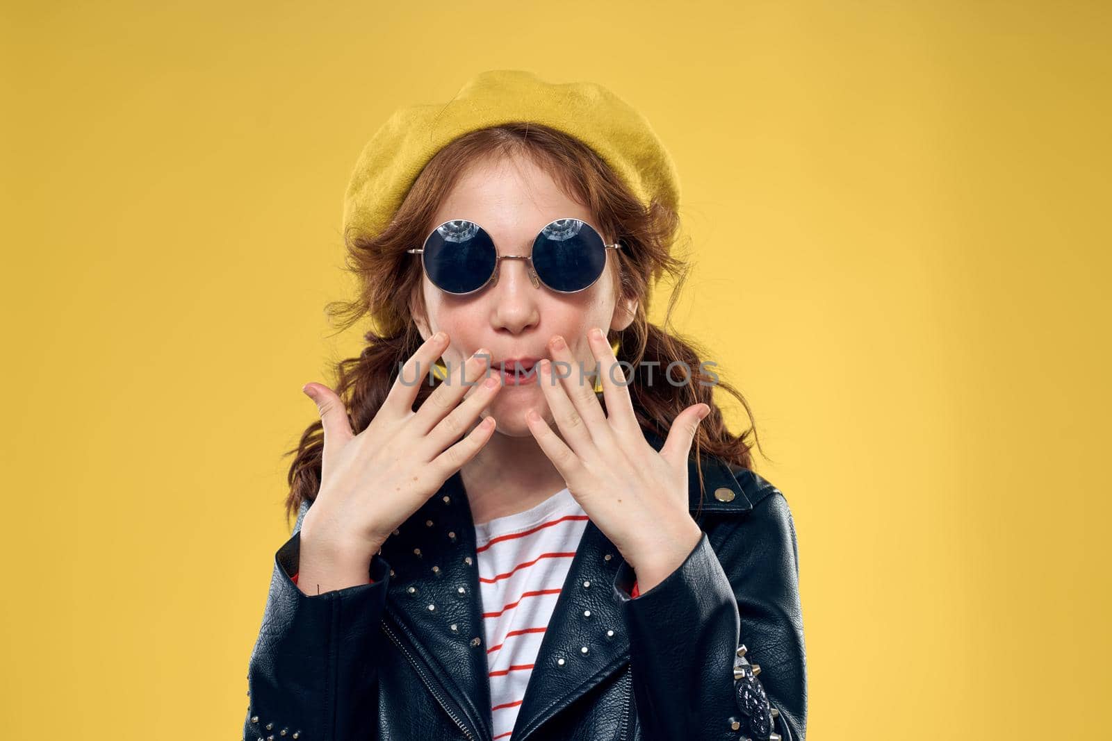Cheerful little girl in sunglasses and hat lifestyle studio yellow background fashion. High quality photo