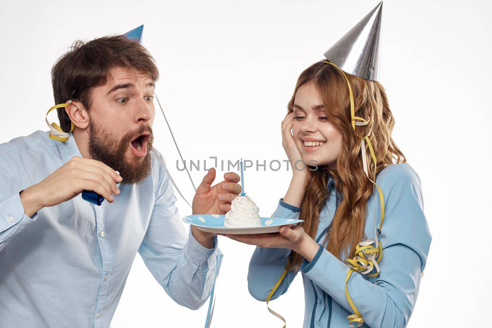 energetic man and woman with a cake and in hats celebrate a birthday on a light background. High quality photo