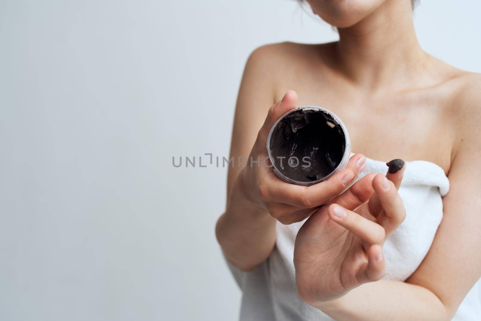 Pretty brunette naked shoulders black cream skin care care close-up. High quality photo