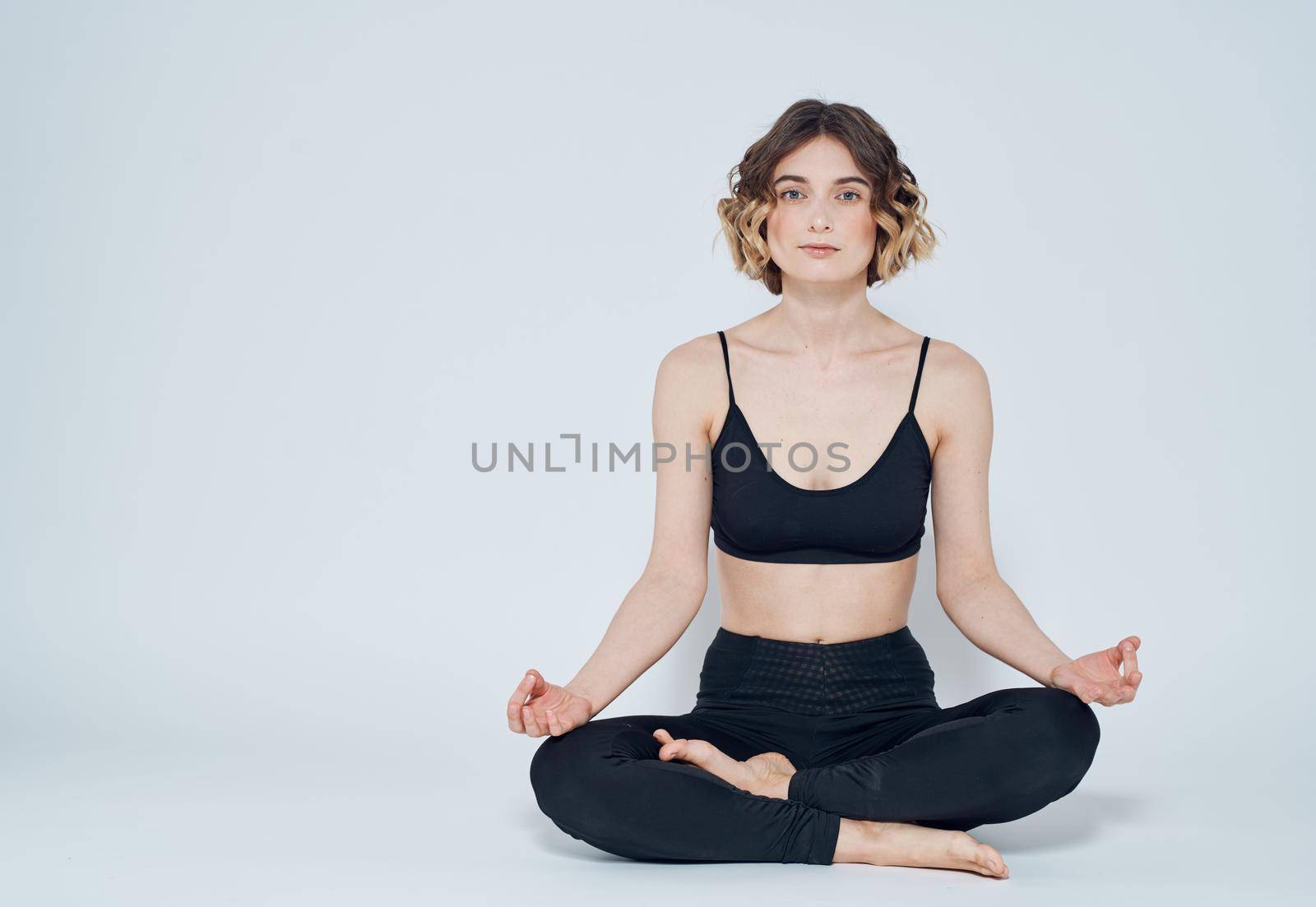 A sportive woman is doing exercises on a light background gesturing with her hands. High quality photo