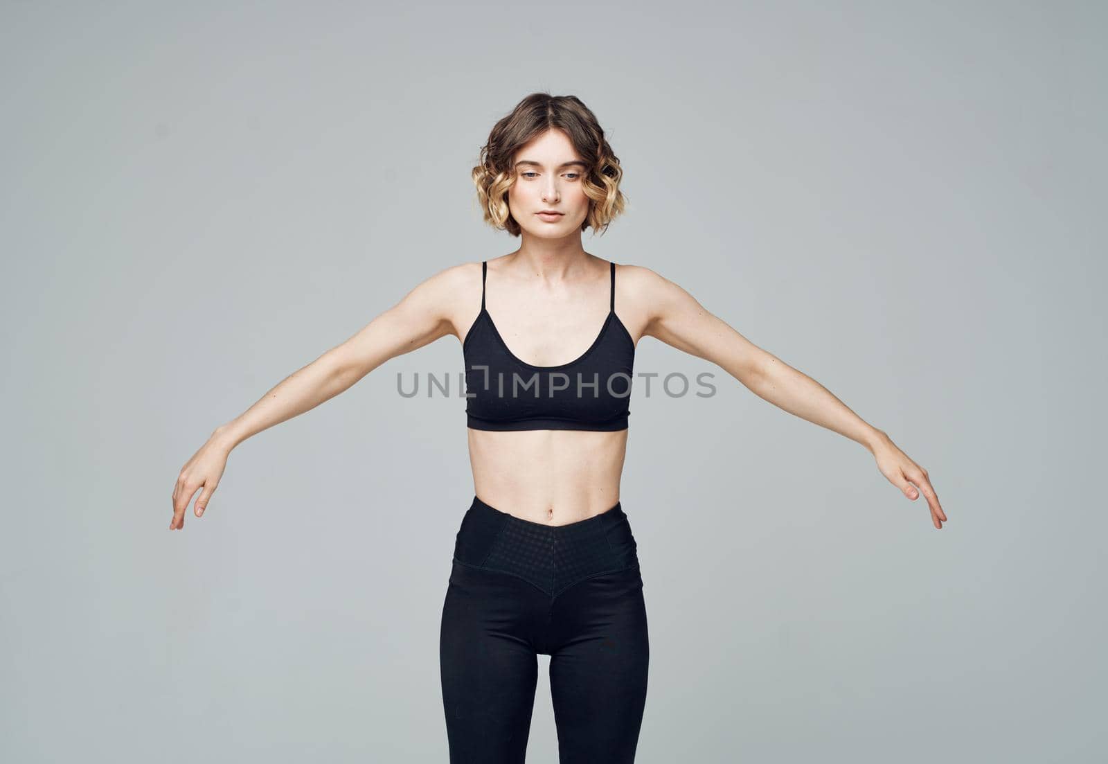 woman in black jeans on gray background doing exercises cropped view by SHOTPRIME