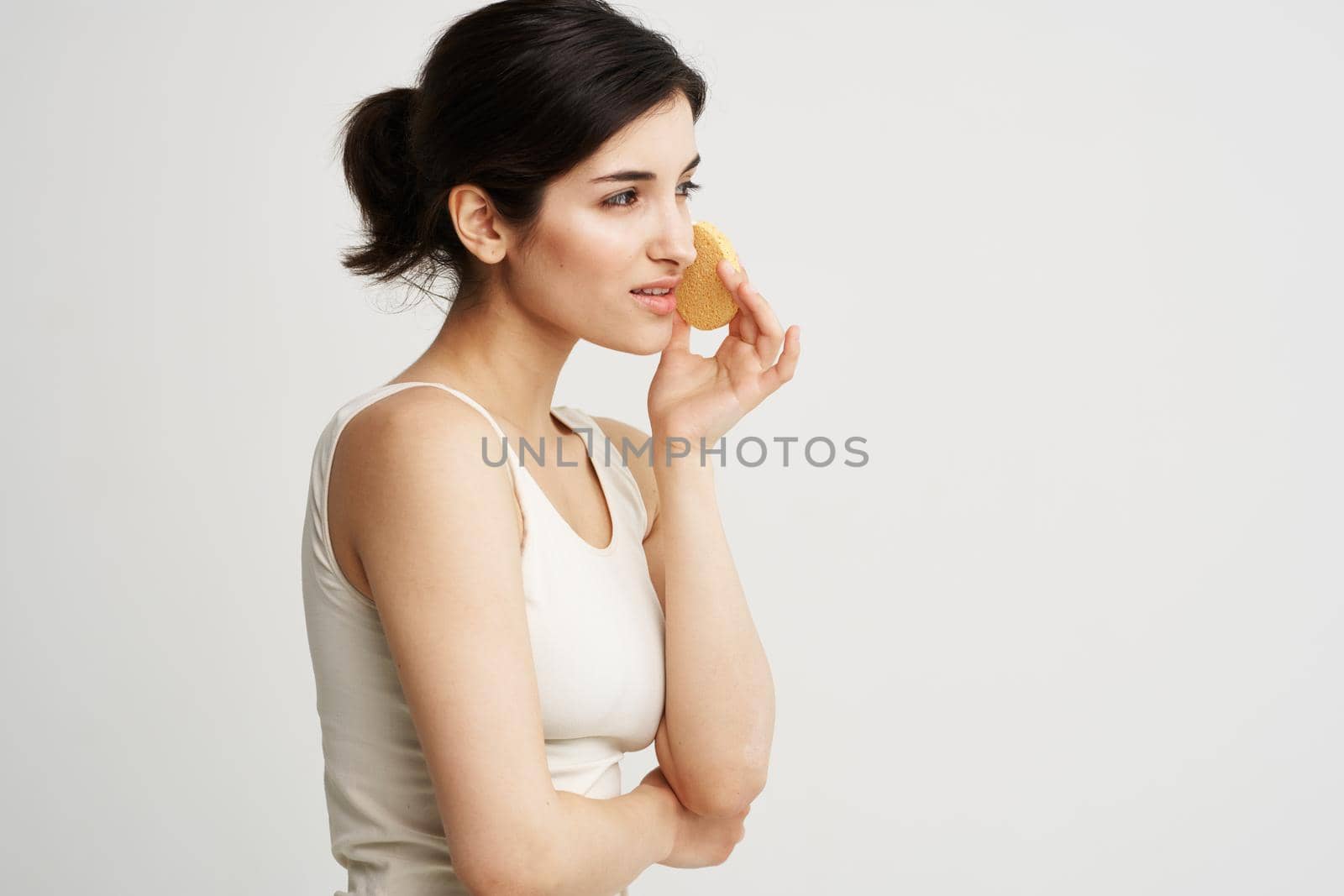 pretty woman in tank top cosmetics skin care makeup remover sponge. High quality photo