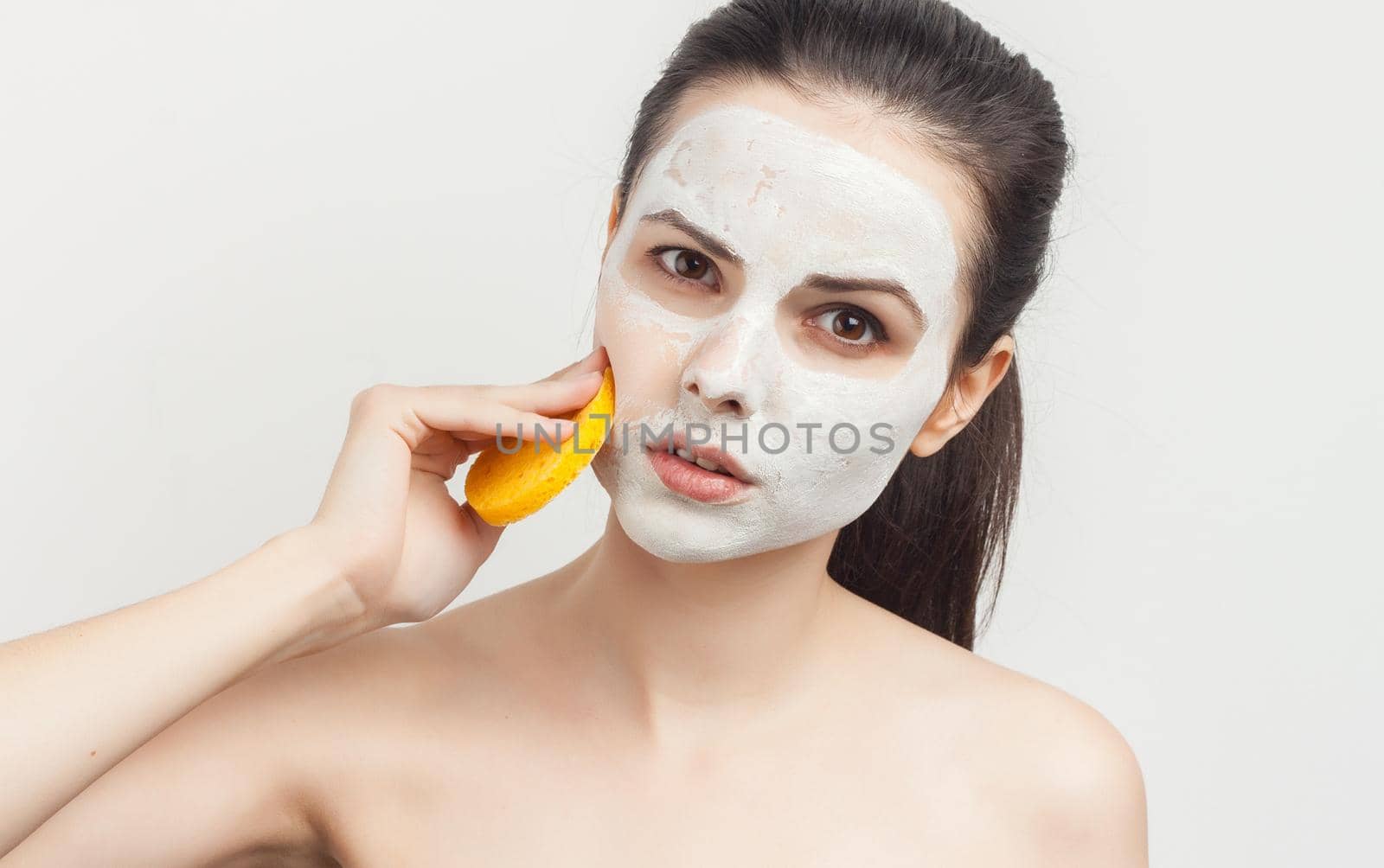 emotional brunette cream face mask bare shoulders cropped view clear skin. High quality photo