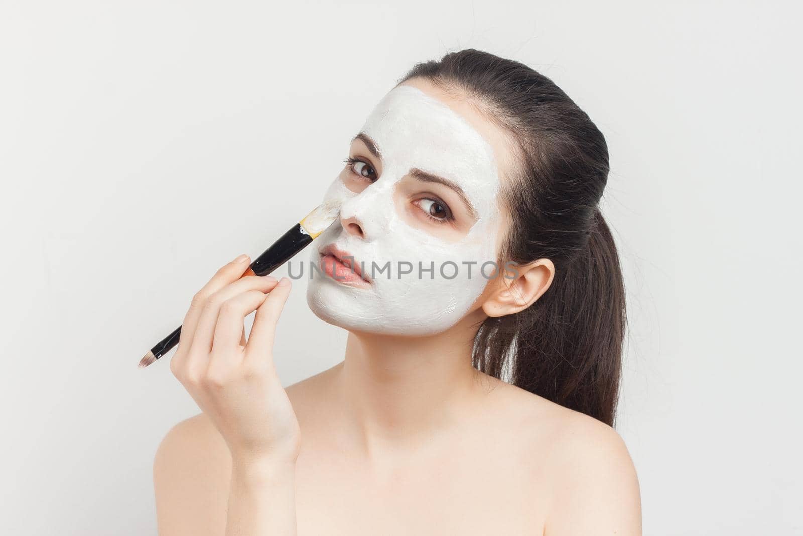 brunette with bare shoulders brush in hand skin care. High quality photo