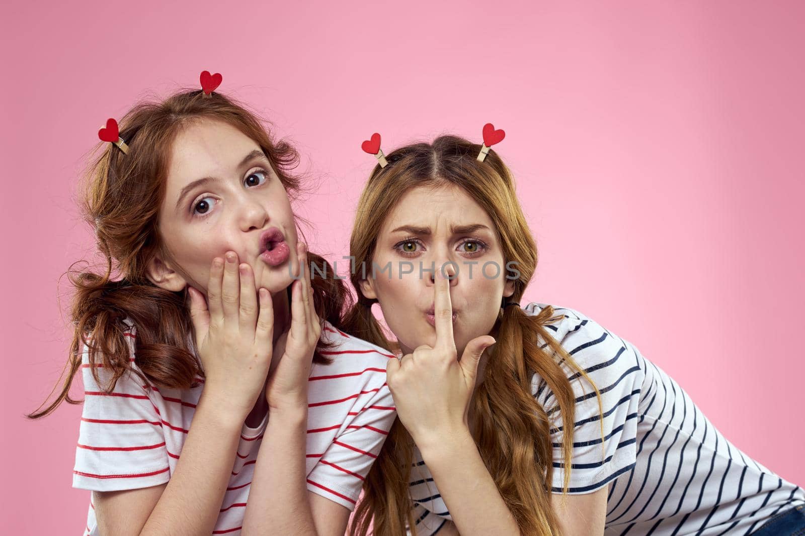 cheerful girl and woman on a pink background sisters family emotions. High quality photo