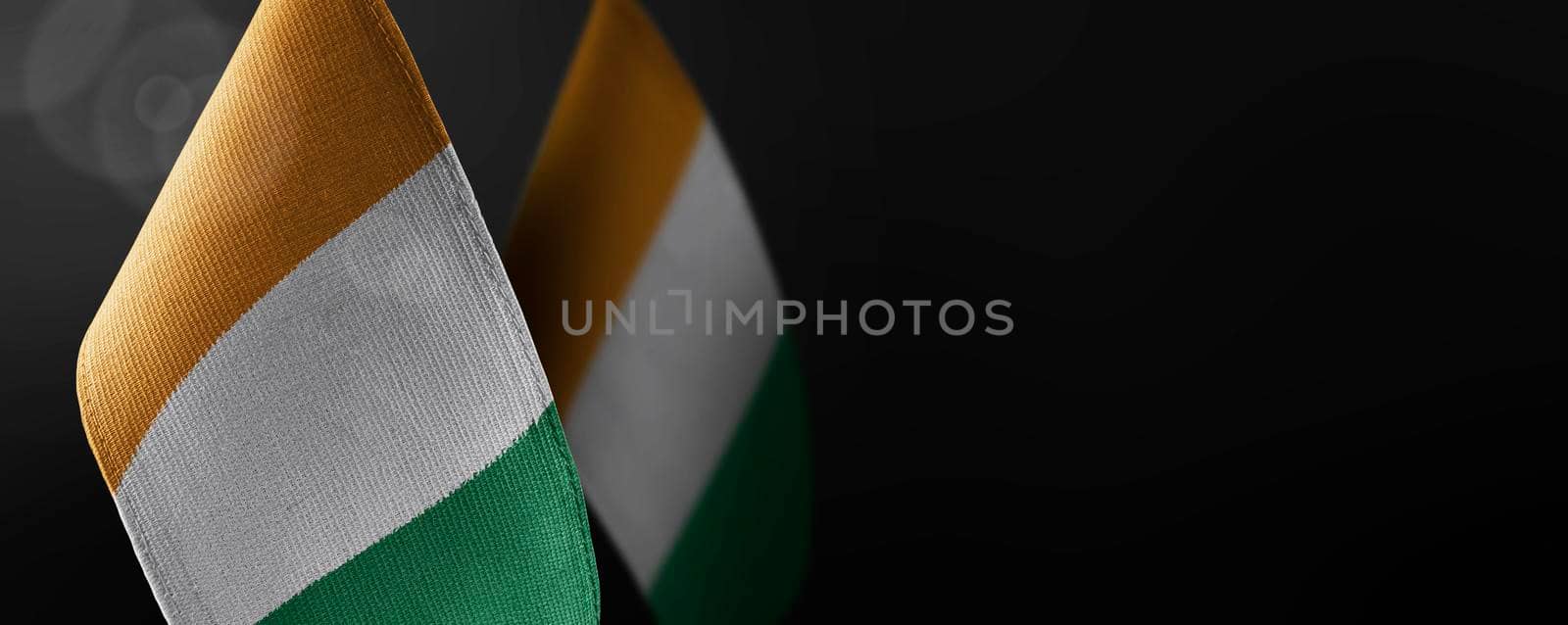 Small national flags of the Cote dIvoire on a dark background.