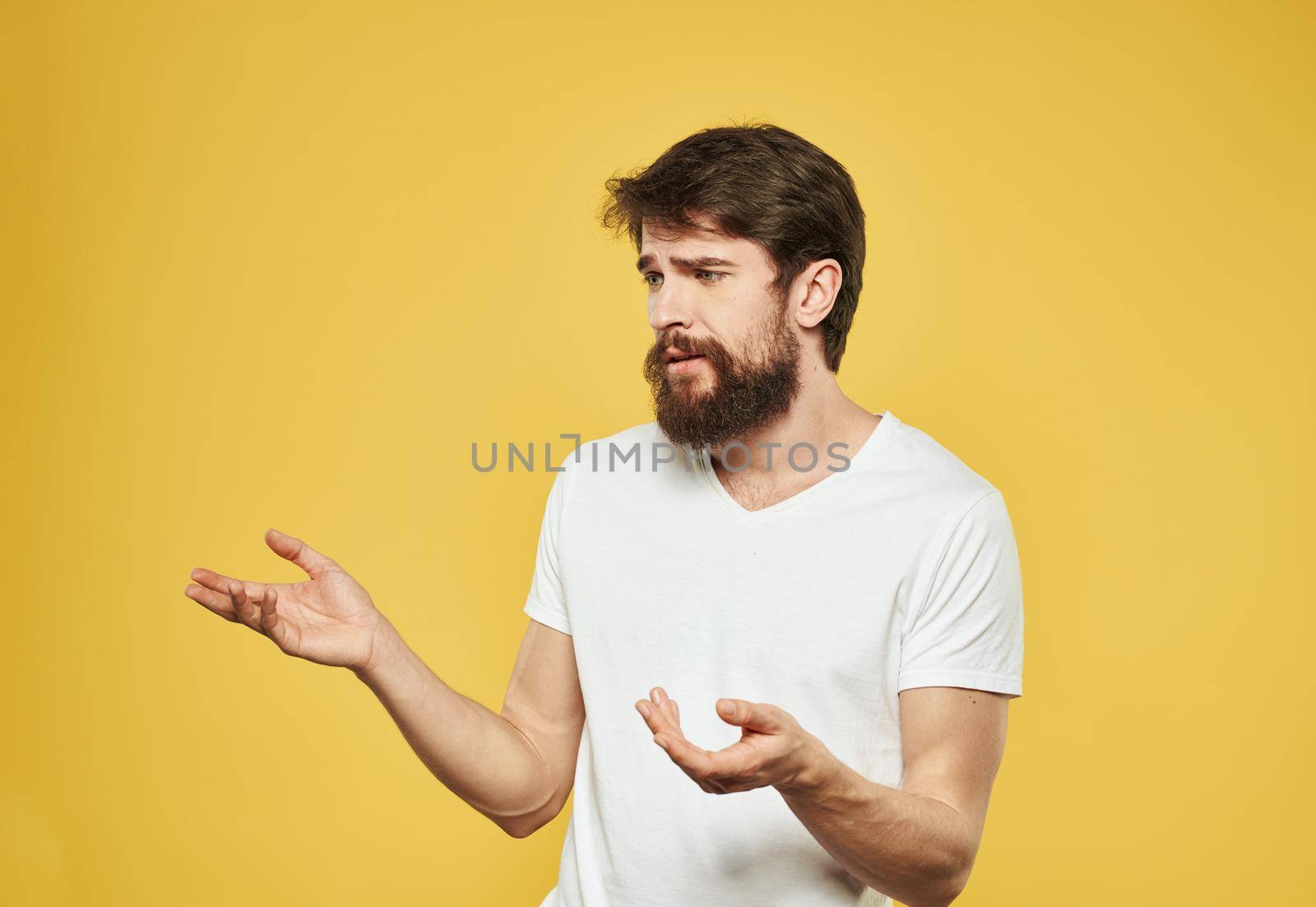 Emotional guy gesturing with his hands on a yellow background model side view. High quality photo