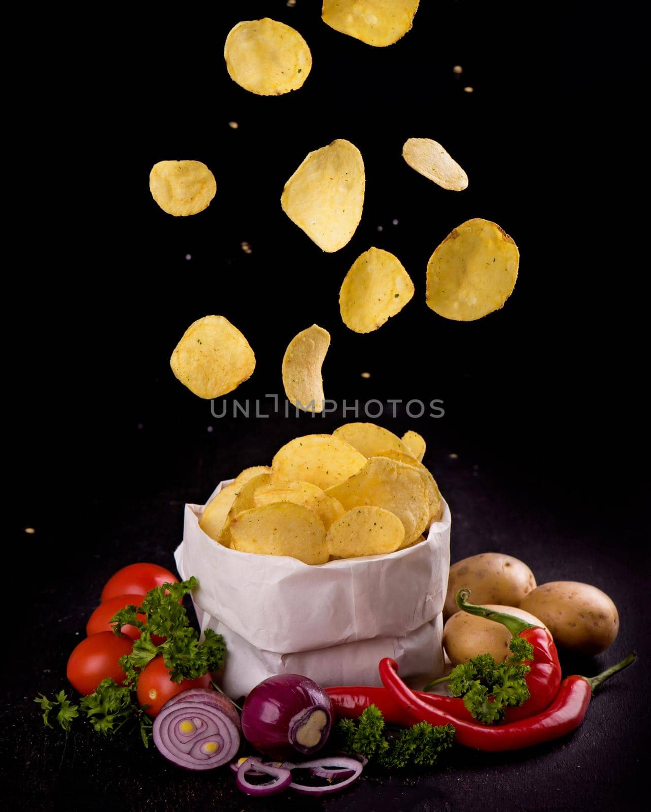 Crispy potato chips in a bag on dark table.