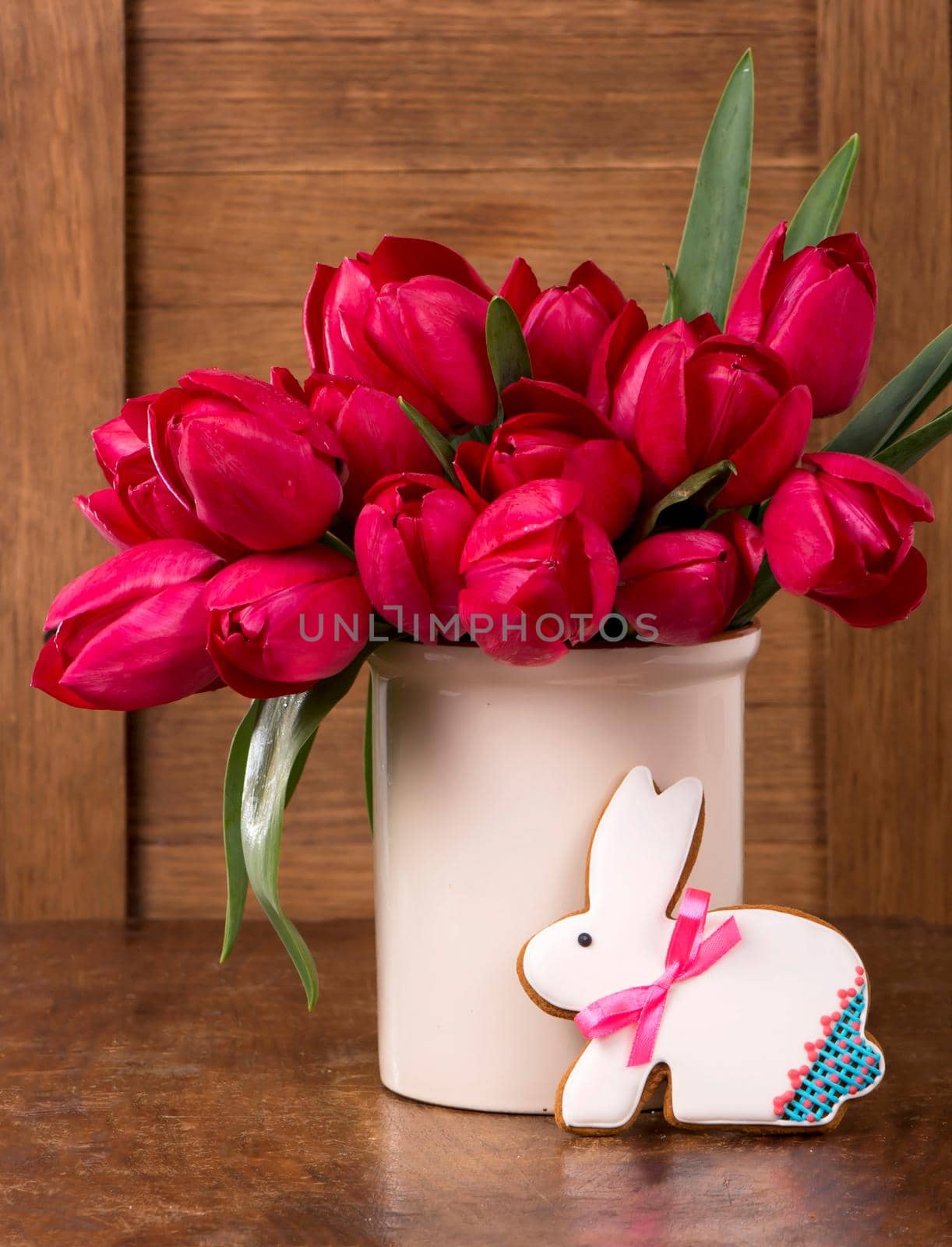 Pink tulips and easter bunny cookie on wooden background. by aprilphoto