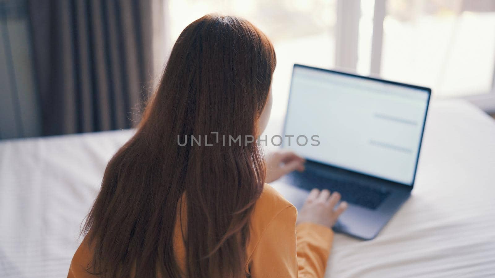 woman in front of laptop lying in bed at home internet communication by SHOTPRIME