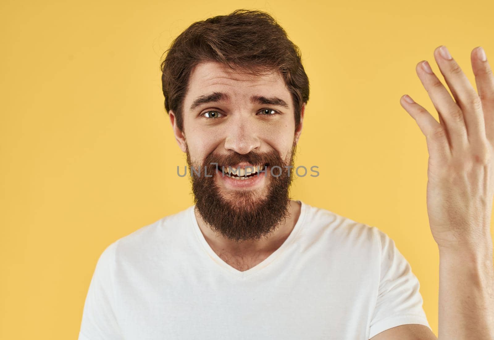 Close-up portrait of a happy man in a white t-shirt on a yellow background. High quality photo