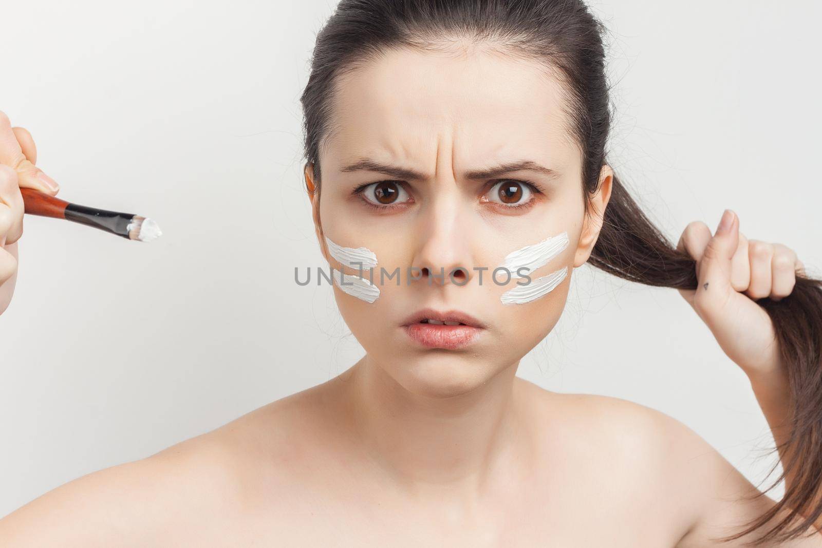 emotional brunette with face mask naked shoulders skincare. High quality photo