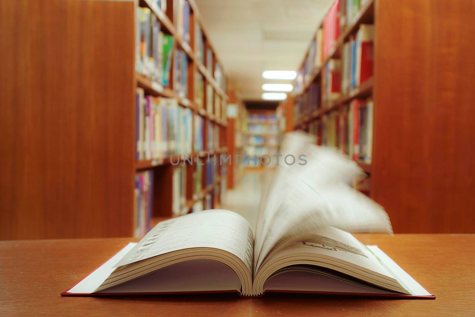 Education learning concept with quickly opening book or textbook in old library, and aisle of bookshelves in library university background