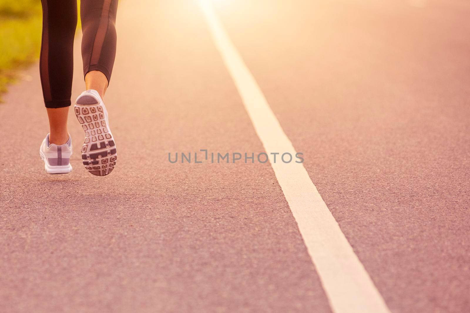 Close up Sporty woman running on road at sunset. Fitness and workout wellness concept.