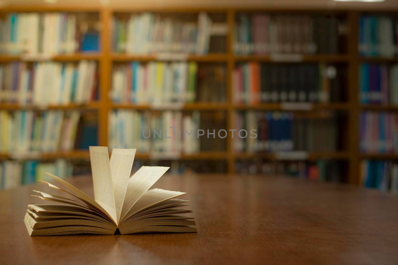 Old open book on the table a bookshelf background for academic education learning concept. by thanumporn