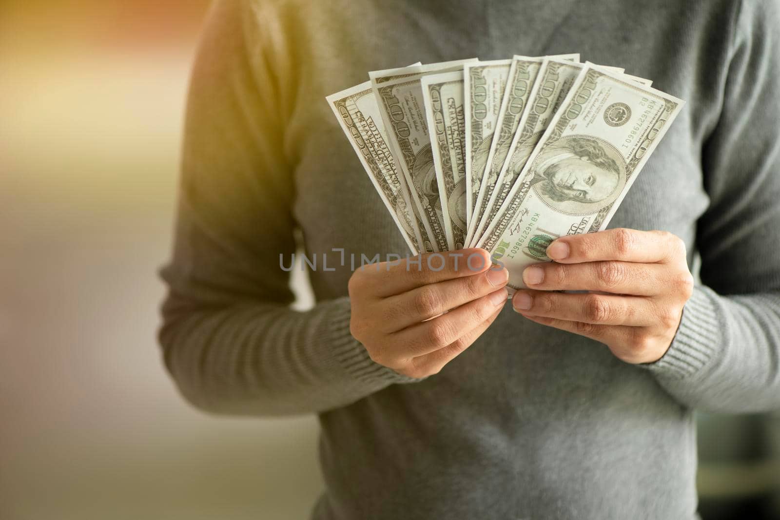 close-up dollars in the hands. Businessman in gray shirt holding. a fan of money by thanumporn