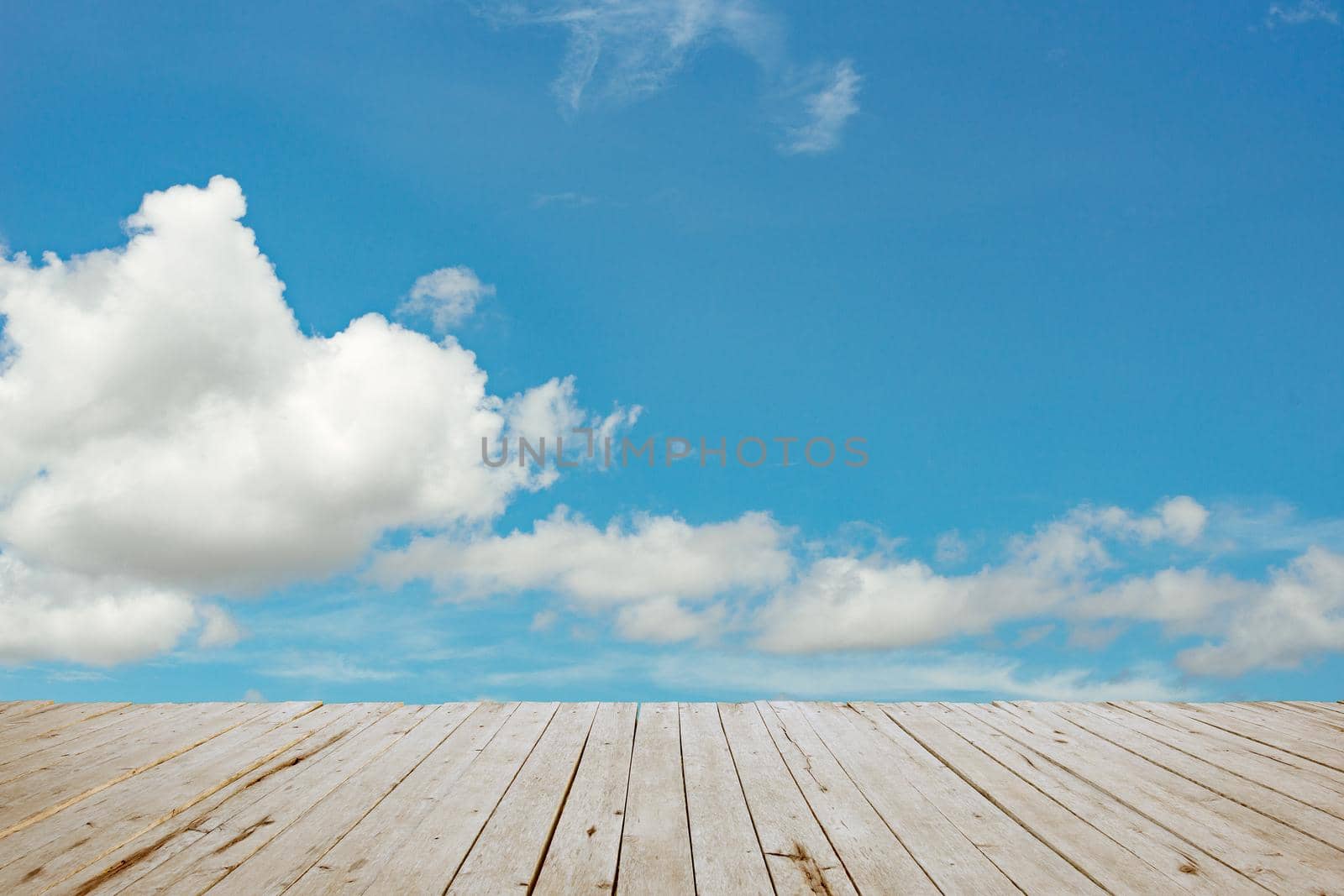 wooden batten bridge juts out into the expanse of the blue cloud sky by thanumporn