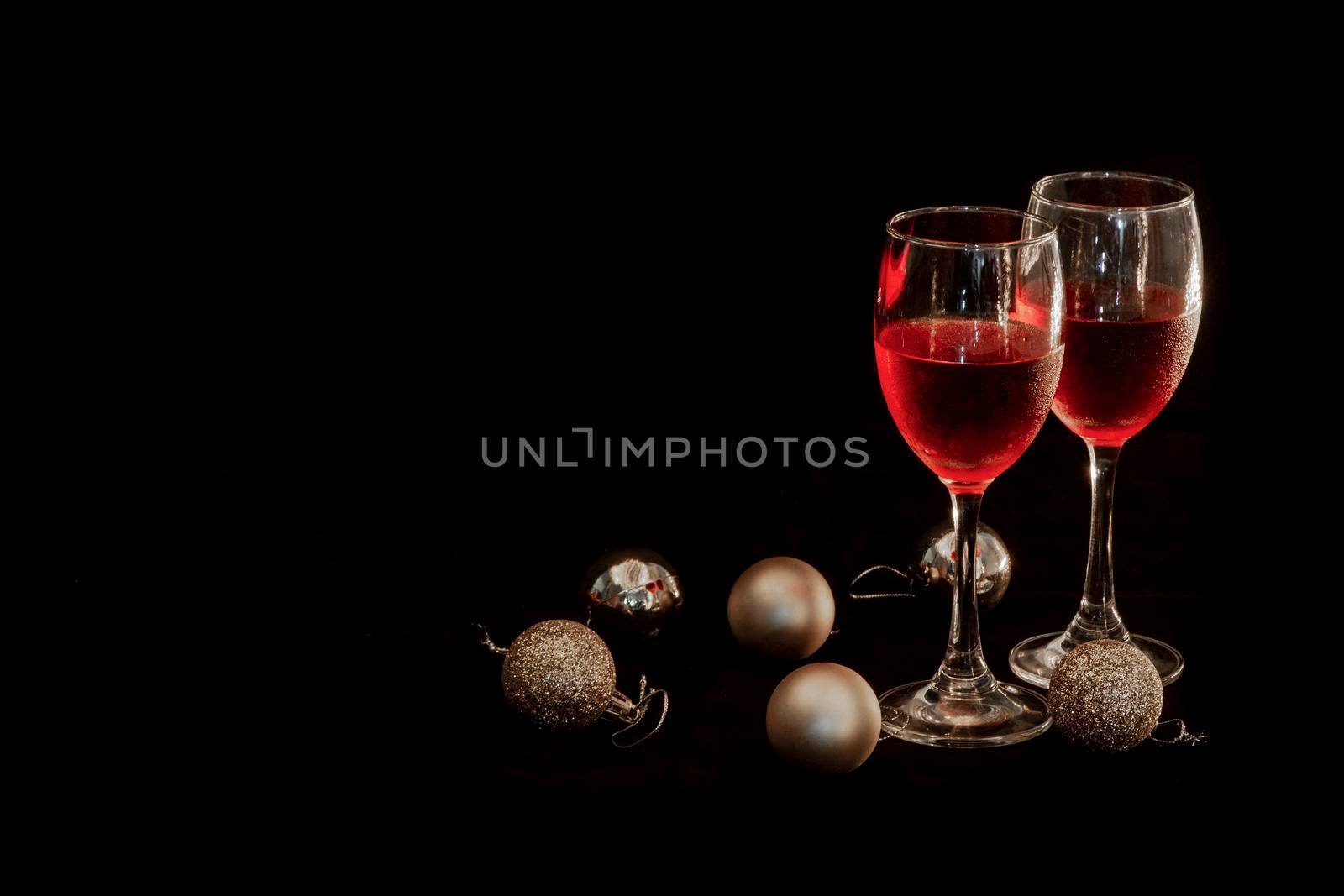Celebration theme with  two red wine glass and Golden round ball on  black background by thanumporn
