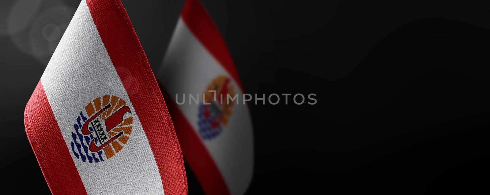 Small national flags of the French Polynesia on a dark background.