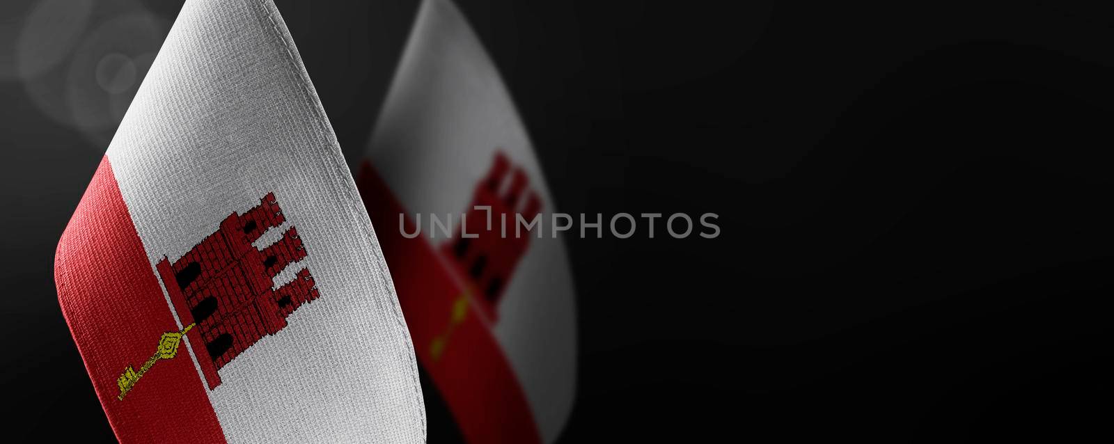 Small national flags of the Gibraltar on a dark background.