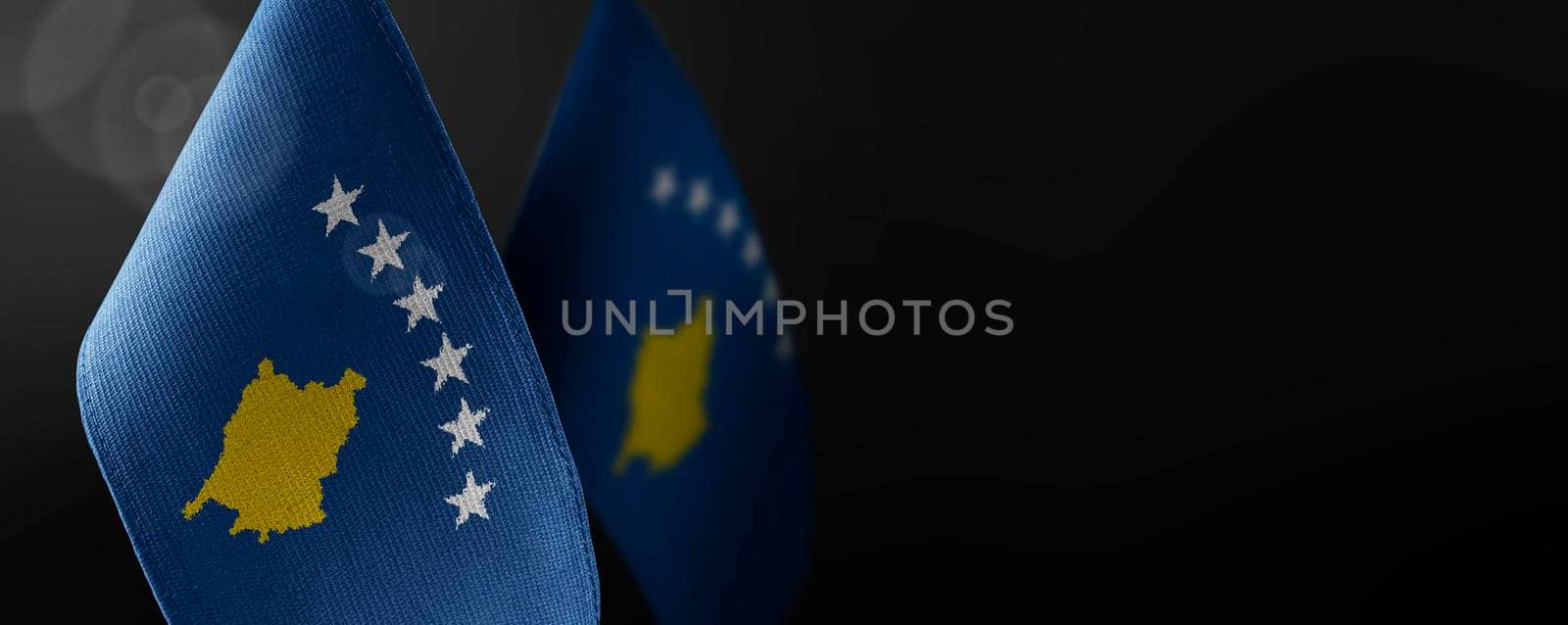 Small national flags of the Kosovo on a dark background.