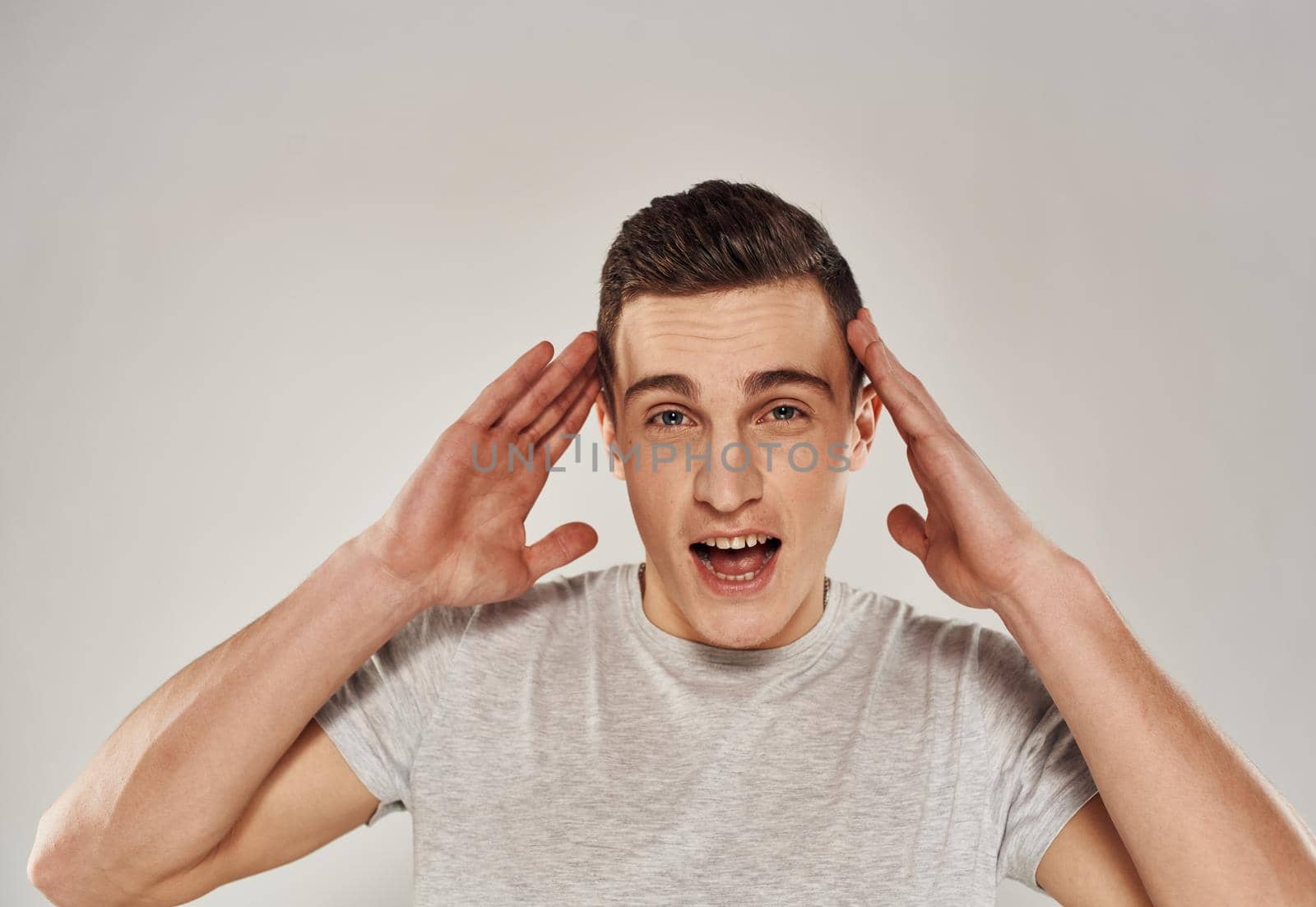 cheerful man gesturing with his hands in a white t-shirt light background cropped view. High quality photo