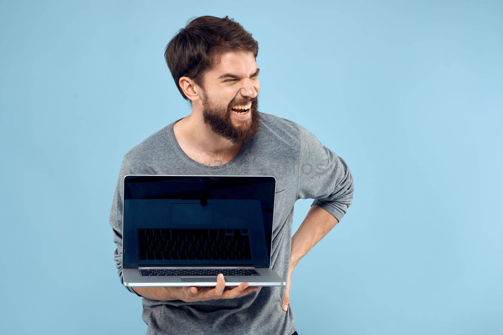 Man with laptop in hands technology communication professionals work blue background. High quality photo